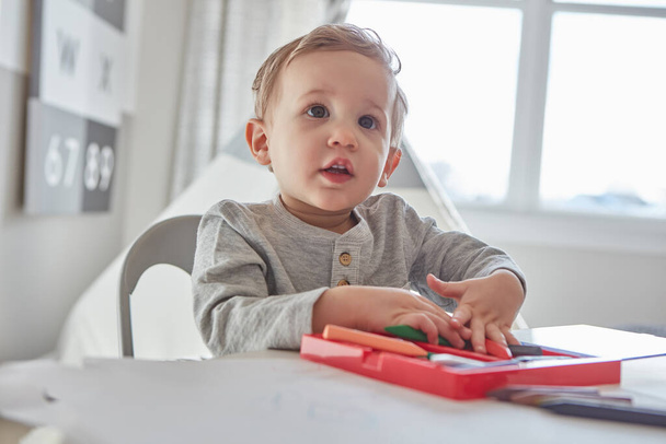 Писать карандашами его любимое занятие. маленький мальчик играет со своими карандашами дома - Фото, изображение
