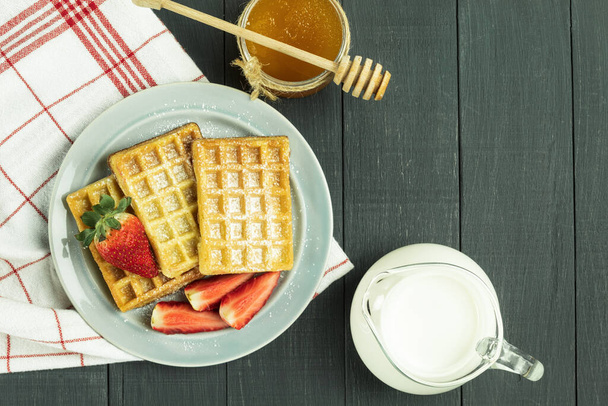 Belgian waffles and fresh fruit on a plate. Gray waffles on a rustic background. copy space. View from above - Photo, Image
