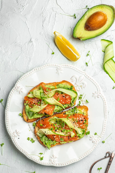 Open sandwiches with salted salmon, guacamole avocado and fresh greens. Delicious breakfast or snack, Clean eating, dieting, vegan food concept. top view - Φωτογραφία, εικόνα