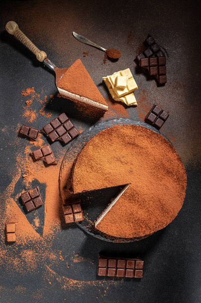 Köstlicher frischer Schokoladenmoussekuchen auf dunklem Hintergrund. vertikales Bild. Ansicht von oben. Platz für Text. - Foto, Bild
