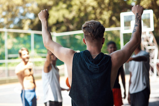 Talent wins games, teamwork wins championships. Rearview shot of a sporty young man cheering with his friends on a sports court - Фото, зображення