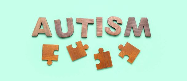 Word AUTISM with jigsaw puzzle pieces on turquoise background - Photo, Image