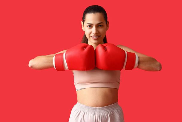 Young woman with boxing gloves on red background - Photo, Image