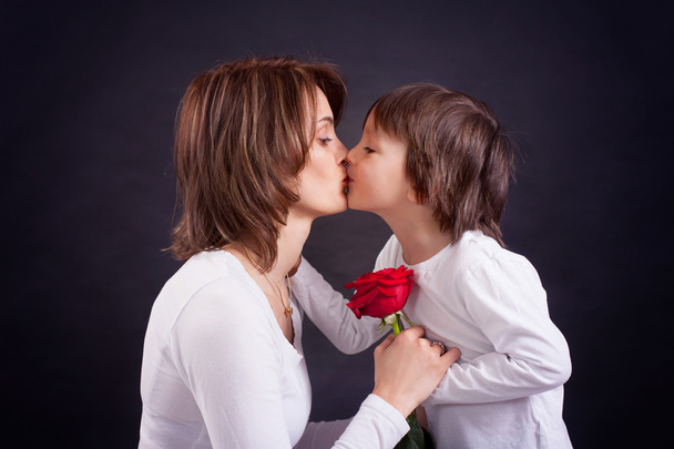 Young kid giving gorgeous red rose to his mom - Fotó, kép