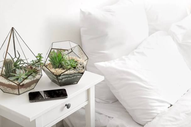 Florariums with mobile phone on table in light bedroom - Photo, Image