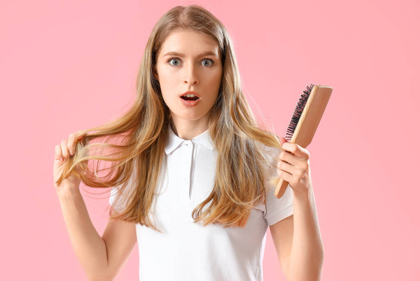 Shocked young woman with hair loss problem and brush on pink background - Valokuva, kuva