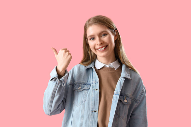 Junge Frau zeigt auf etwas auf rosa Hintergrund - Foto, Bild