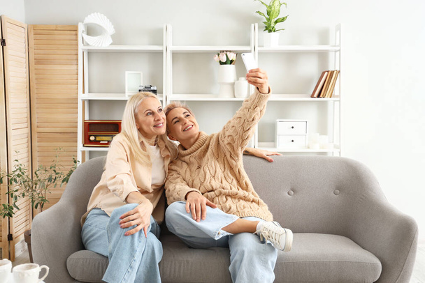 Joyeuses femmes mûres prenant selfie à la maison - Photo, image