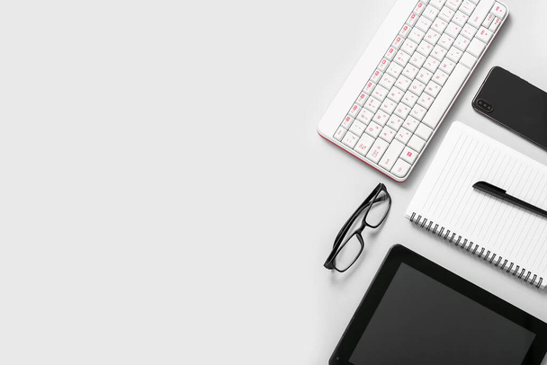 Komposition mit Tablet-Computer, Brille, Tastatur und Handy auf weißem Hintergrund - Foto, Bild