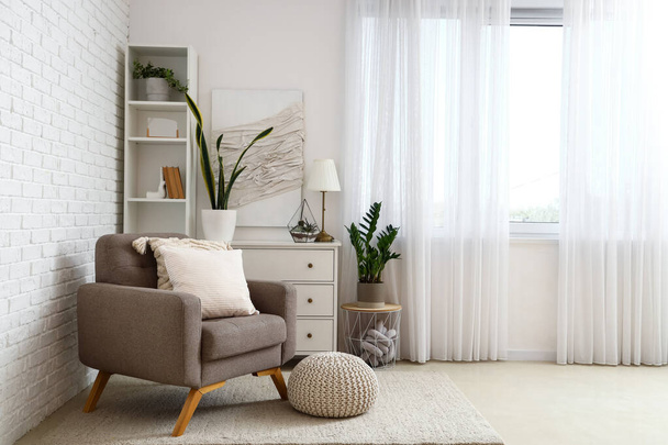 Gemütlicher grauer Sessel mit Kissen im Innenraum eines hellen Wohnzimmers - Foto, Bild