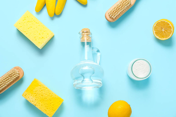 Jarra de vinagre, bicarbonato de sodio, cepillos, esponjas y limones sobre fondo de color - Foto, imagen