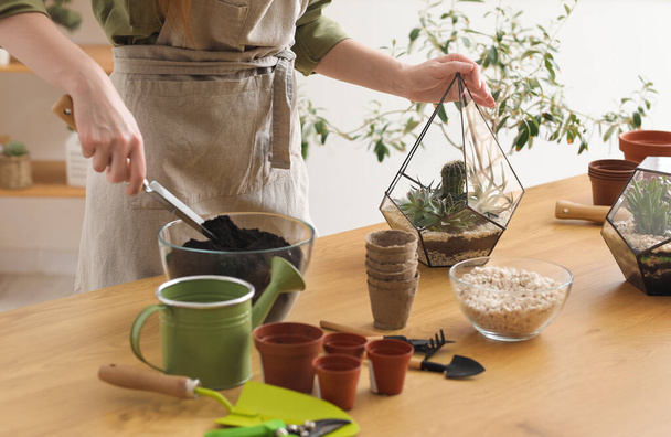 Vrouwelijke tuinman maken van florarium op tafel thuis, close-up - Foto, afbeelding