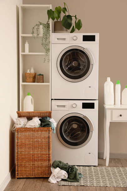 Interior of laundry room with washing machines, table and basket - Foto, imagen