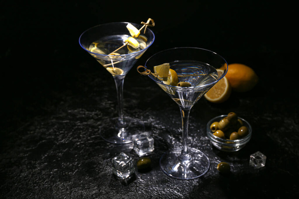 Copos de martini saboroso, cubos de gelo, azeitonas verdes e limão no fundo escuro - Foto, Imagem