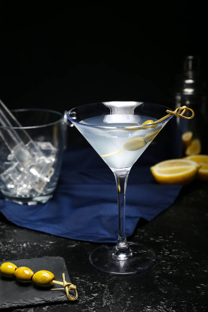 Egy pohár finom martini, vödör jégkockákkal és olajbogyókkal sötét háttéren, közelkép - Fotó, kép