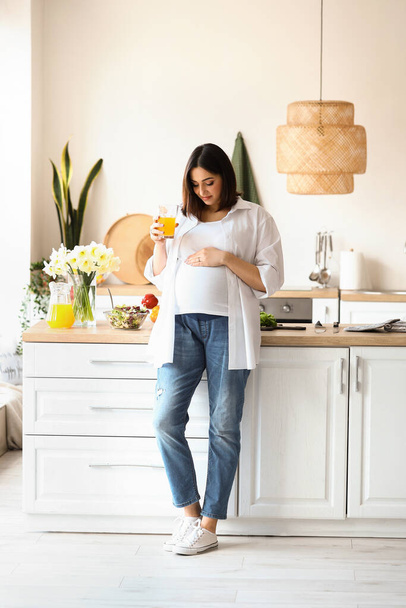 Mujer embarazada joven con vaso de jugo en la cocina - Foto, imagen