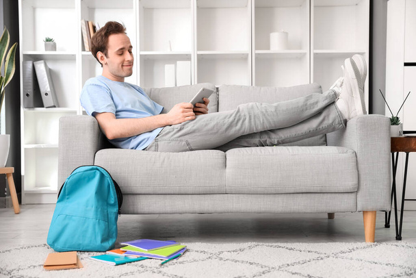 Мужчина с планшетным компьютером лежит дома на диване - Фото, изображение