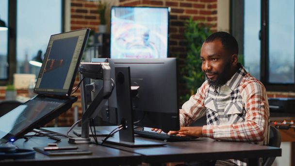 Afro-Amerikaanse mannelijke kunstenaar werkt in studio kantoor om CGI productie te creëren op software, digitale vaardigheden. Creatief bureau ontwerper met behulp van professionele interface om infographics te ontwikkelen. - Foto, afbeelding