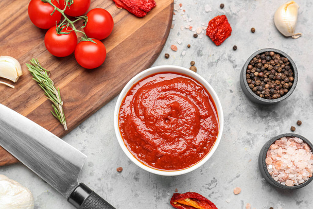 Composition avec bol de sauce tomate et ingrédients sur table grise - Photo, image