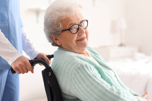 Vanhempi nainen pyörätuolissa hoitajan kanssa kotona, lähikuva - Valokuva, kuva