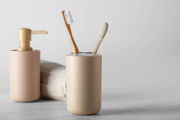 Soporte de cepillos de dientes de bambú y accesorios de baño en mesa blanca - Foto, imagen
