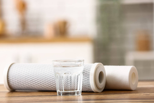 Glass of water with filters on wooden table in kitchen - Photo, image