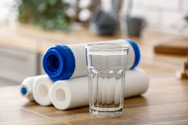 Szklanka wody z filtrami na drewnianym stole w kuchni - Zdjęcie, obraz