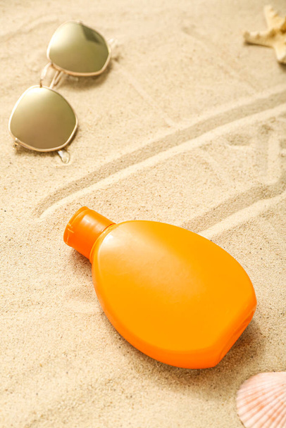 Composition créative avec bouteille de crème solaire avec lunettes de soleil sur sable - Photo, image