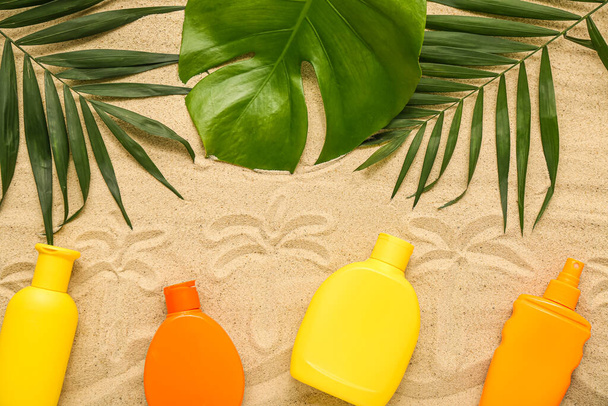 Luova koostumus eri aurinkovoidetta voiteet ja palmunlehtiä hiekalla - Valokuva, kuva