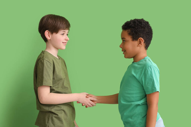 Маленькі хлопчики тримають руки на зеленому фоні. Дитячий день - Фото, зображення