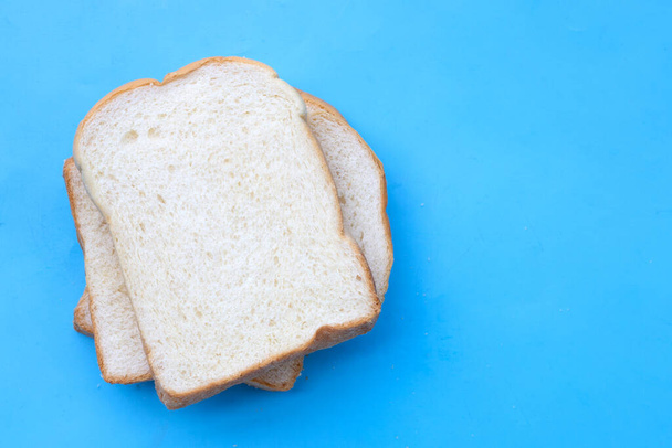 Κομμένο ψωμί σε μπλε φόντο. - Φωτογραφία, εικόνα
