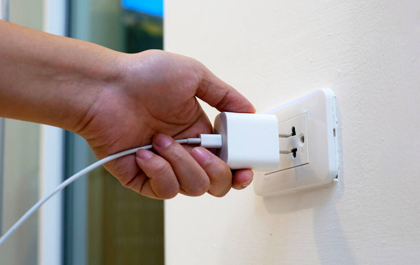 Hand insert a plug of the phone charger into socket. - Foto, Bild