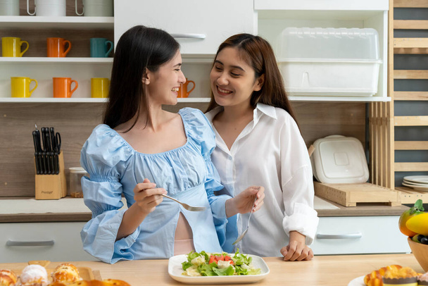 Asian young pretty woman and her girlfriend eating meal with happiness together in kitchen, the moment romantic time of female lover, LGBTQ freedom of love concept, copy space - Foto, Imagem
