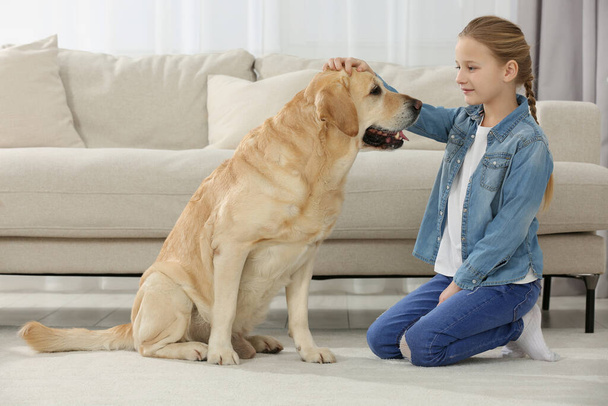 Cute child with her Labrador Retriever on floor at home. Adorable pet - Foto, immagini