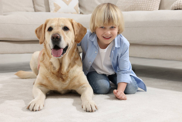 Cute little child with Golden Retriever on floor at home. Adorable pet - Фото, зображення