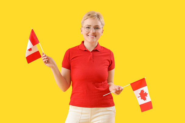 Giovane donna con bandiere del Canada su sfondo giallo - Foto, immagini