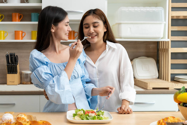 Asian young pretty woman and her girlfriend eating meal with happiness together in kitchen, the moment romantic time of female lover, LGBTQ freedom of love concept, copy space - Foto, afbeelding