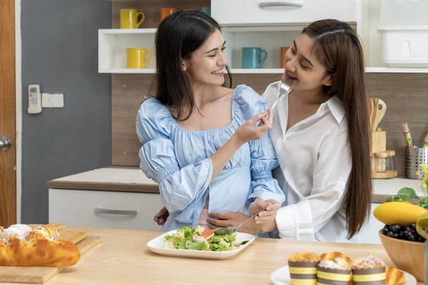 Asian young pretty woman and her girlfriend eating meal with happiness together in kitchen, the moment romantic time of female lover, LGBTQ freedom of love concept, copy space - Φωτογραφία, εικόνα
