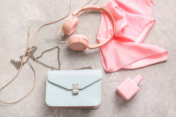 Elegante bolso con auriculares y perfume sobre fondo grunge gris - Foto, imagen