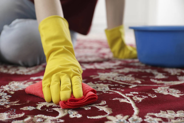 Woman in rubber gloves cleaning carpet with rag indoors, closeup. Space for text - Foto, afbeelding