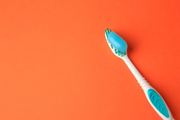 Brush and toothpaste on orange background, above view. Space for text - Foto, Imagem