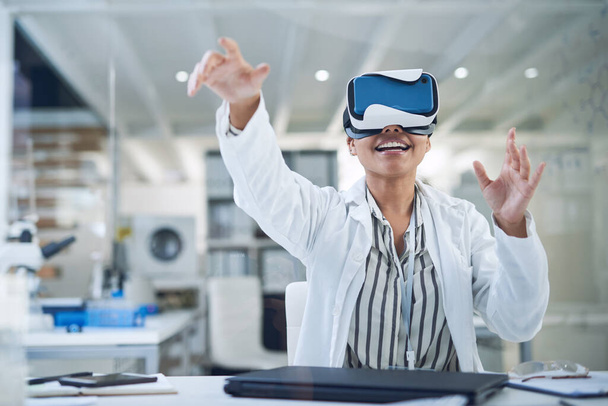Gegevens uit een nieuwe wereld halen. een jonge wetenschapper met behulp van een virtual reality headset tijdens het werken in een lab - Foto, afbeelding