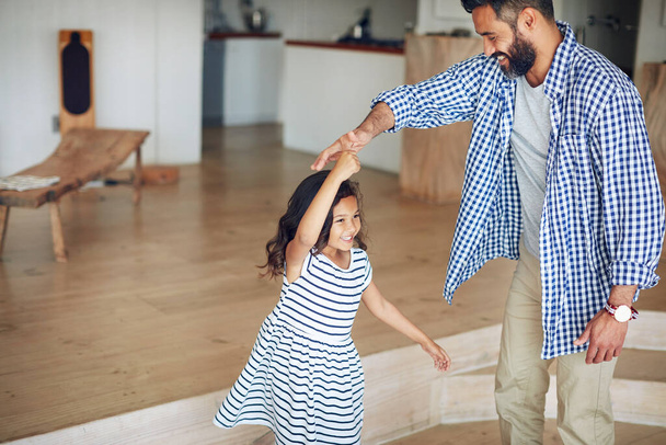 Οικογένεια, πατέρας και κορίτσι χορεύουν, σπίτι και ευτυχία με αγάπη, δέσιμο και κίνηση στο σαλόνι. Αρσενικό γονέα, θηλυκό παιδί και κόρη με τον μπαμπά, παιδί και χορό για διασκέδαση, παιχνιδιάρικο και αγάπη μαζί. - Φωτογραφία, εικόνα