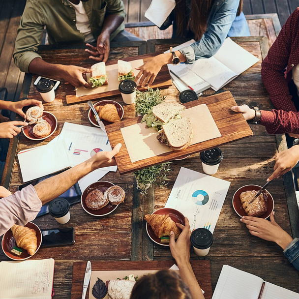 Tener un almuerzo productivo. Foto de alto ángulo de un grupo de trabajadores creativos en un almuerzo de negocios - Foto, Imagen