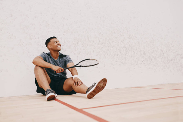 Minden tőled telhetőt megtettél, hogy pihenj. egy fiatalember szünetet tart, miután squash-t játszott. - Fotó, kép