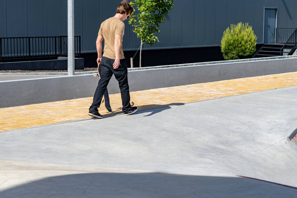Man walking and holding a skateboard on a urban scene. - Фото, зображення