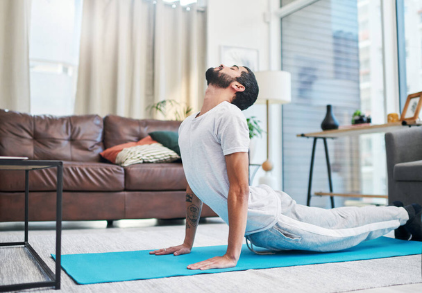 Yoga é para todos e qualquer um. um jovem bonito praticando ioga em sua sala de estar em casa - Foto, Imagem