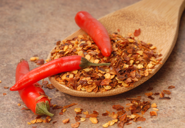 rode chili peppers en rode peper vlokken op een lepel - Foto, afbeelding