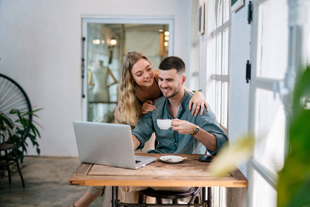Couple souriant regardant ordinateur portable ensemble au bureau à la maison confortable. Le concept de couples partageant une idée ensemble. - Photo, image
