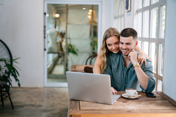 Jeune couple utilisant un ordinateur portable sur le bureau à la maison et réfléchir. Le concept de couples partageant une idée ensemble. - Photo, image
